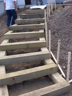 the man is walking up some stairs made out of wooden planks and plywood