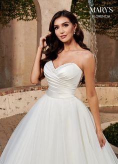 a woman in a wedding dress posing for the camera with her hand on her shoulder