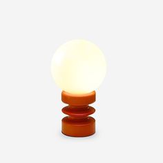 an orange table lamp sitting on top of a white surface