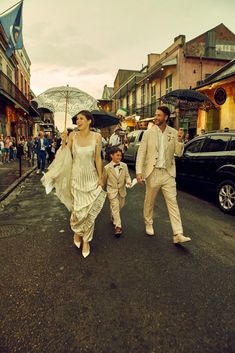 a man and woman are walking down the street with an umbrella over their heads while a small boy is holding his hand