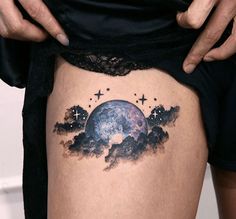 a woman's thigh with an earth tattoo on the side and stars in the sky