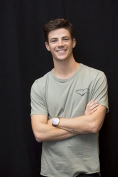 a man standing with his arms crossed in front of a black background wearing a green t - shirt