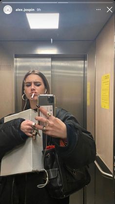 a woman taking a selfie in an elevator with her phone up to her ear