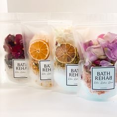 three bags of bath reha with orange slices and flowers in them on a white surface