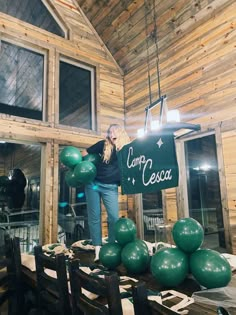 a woman standing in front of a sign that says comfy cesar on it with balloons around her