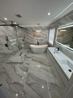 a bathroom with marble walls and flooring has a large bathtub in the middle