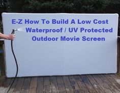 a man sprays water on a sign that reads ez how to build a low cost waterproof / u - v protected outdoor movie screen