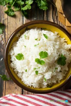 white rice with cilantro and parsley in a yellow bowl on a striped napkin