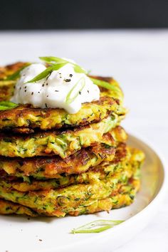 a stack of zucchini fritters with sour cream on top