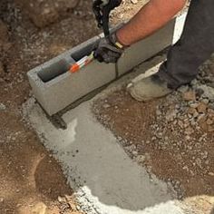 a man is pouring cement into a hole