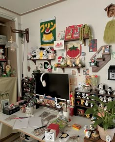 a cluttered desk with lots of stuff on the top and shelves above it that are filled with various items