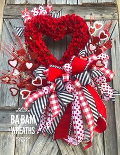 a heart shaped wreath with red roses and hearts hanging on the front door for valentine's day