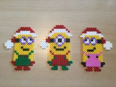 three minion perler beads sitting on top of a wooden table