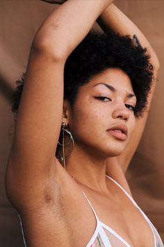 a close up of a woman with her hair in the air and wearing large hoop earrings