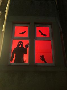 the silhouettes of two people are seen through an open window with red light coming from them