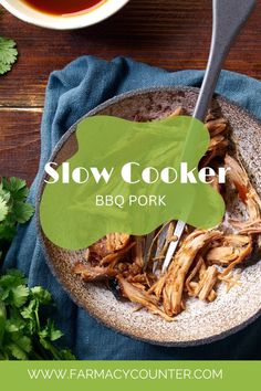 slow cooker bbq pork in a bowl with parsley next to it on a blue towel