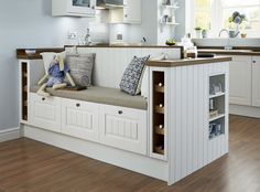 a kitchen with wooden floors and white cabinets, including a bench that is built into the wall