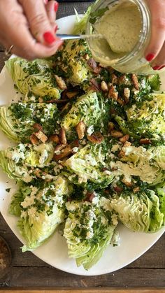 a plate with lettuce, bacon and dressing on it next to a woman's hand