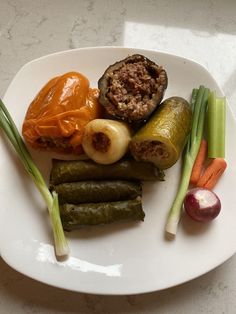 a white plate topped with different types of vegetables and meat on top of each other