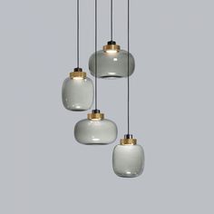 three white and gold glass pendants hanging from a ceiling fixture in a gray room