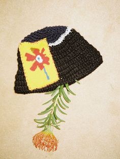 a crocheted hat with a flower attached to it sitting on top of a table