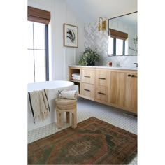 a bath room with a tub a mirror and a rug on the floor in front of it