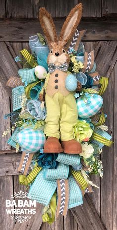 a wreath with an easter bunny in the center and blue, green, and white ribbons around it