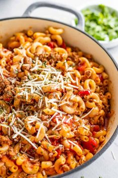 a skillet filled with pasta and meat topped with parmesan cheese