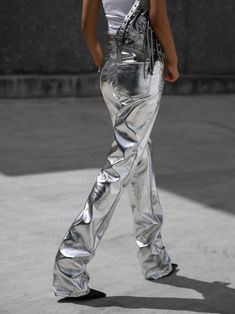 a woman walking down the street in silver pants