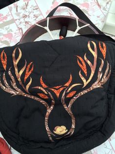 a black bag with an orange and yellow deer design on the front, sitting on top of a table