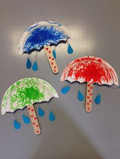 three umbrellas made out of popsicle sticks with paint on them