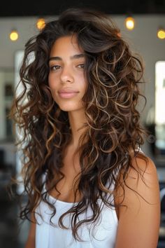 Discover the beauty of your natural curls with these 25 gorgeous layered curly hairstyles. Say goodbye to constant flat ironing and explore styles that enhance your unique texture. Embrace the volume and dimension of your curls with these stunning haircut ideas that will leave you feeling confident and empowered. Choose a layered curly hairstyle that suits your personality and lets your natural beauty shine bright! Highlights Brown Hair Natural Curls, Salon Curls Hairstyles, Volume Curly Haircut, Curly Brown Hair Highlights, Natural Curly Hair With Highlights, Natural Curly Haircut, Honey Blonde Balayage Curly Hair, Fall Curly Hairstyles, Salon Curls