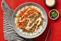 a bowl filled with rice, meat and veggies next to chopsticks