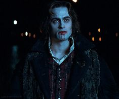 a man with blood all over his face and mouth standing in the dark at night