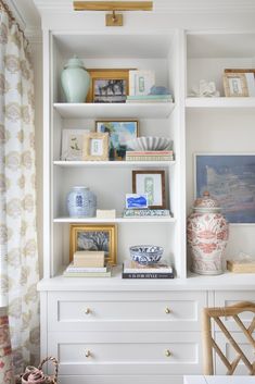 a white bookcase filled with books and vases