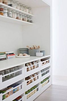 an organized pantry with white shelves and drawers