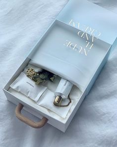 an open box with some items inside on a white sheeted surface, including rings and bracelets