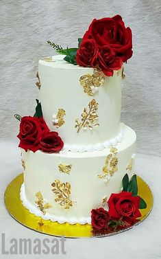 a three tiered cake with red roses on top and gold trim around the edges