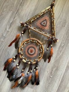 a dream catcher with feathers and beads on the floor next to a wooden wall hanging