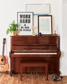 there is a piano in the living room with pictures on the wall and a guitar next to it