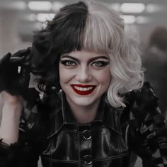 a close up of a person wearing a black jacket and red lipstick with her hands on her head