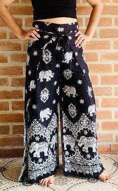 a woman standing in front of a brick wall wearing black and white pants with elephants on them