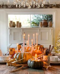 a wooden table topped with candles and pumpkins