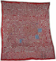 a red and white quilted blanket with blue flowers on the front, in an old fashion