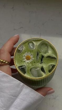 a hand holding a cup filled with green liquid