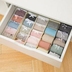 an open drawer filled with lots of different colored items on top of a wooden floor