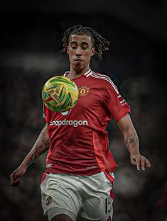 a man with dreadlocks is holding a soccer ball