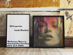 two framed posters sitting on top of a wooden floor next to each other in front of a wall