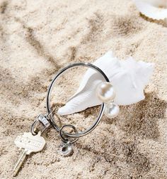 a seashell and keychain on the sand with a sea shell in it