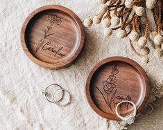 two personalized wooden plates with wedding rings on them next to some dried flowers and beads